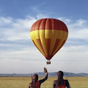 Two Msai warriors watch a hot air balloon flight over Masai Mara