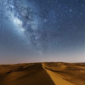 Oman, Wahiba Sands. The sand dunes at night lit by the moon with the milky way