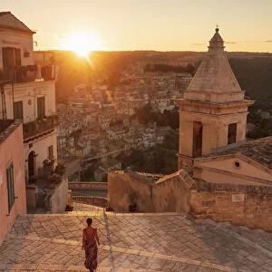 Ragusa Ibla, Sicily. A woman walking on the stairs with Ragusa old town in the background