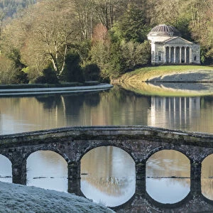 View across Turf Bridge and Garden Lake to the Pantheon, in the grounds of Stourhead, Wiltshire, England. Winter (January) 2022