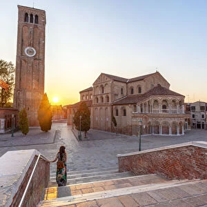 A woman admires the Church of Santa Maria e San Donato (Murano Cathedral) at sunset