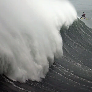 A surfer drops in on a large wave at Praia do Norte, in Nazare