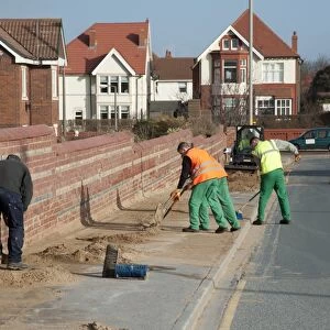 Council workers clearing away sand blown from beach and dunes onto road and pavement in seaside resort town, Lytham St. Anne's, Lancashire, England, january