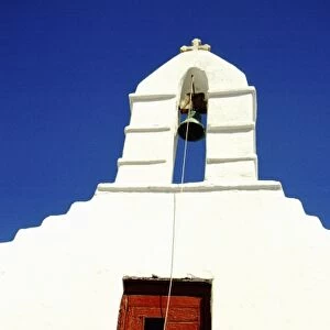 Greece, Aegean Sea, Mykonos. Typical white island church tower with bell and red door