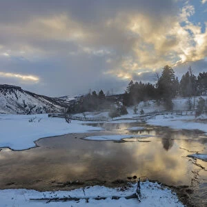 Sunrise clouds reflect into Grassy Spring in winter in Yellowstone National Park