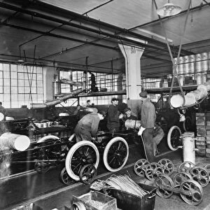 FORD ASSEMBLY LINE, c1913. Workers installing gas tanks at the assembly line at