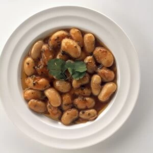 Bowl of Gigantes beans garnished with coriander leaf, a typical dish from Greece, view from above