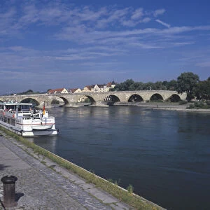 Germany, Bavaria, Regensburg, ratisbon, the picturesque Steiner Brucke, an outstanding example of medieval engineering spanning the Danube, leading to the old town of Regensburg. Passenger boats line the edge of the river
