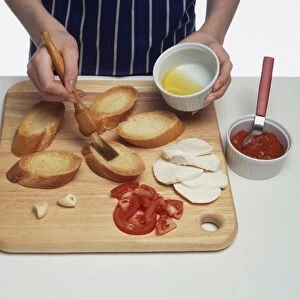 Girl basting crostini toast with olive oil on chopping board