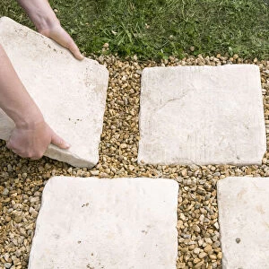 Hand positioning paving slabs on ground