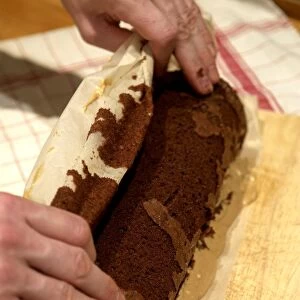 Hands rolling chocolate log filled with cream