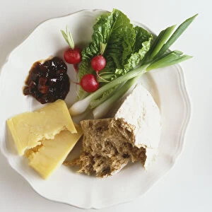 Ploughmans lunch plate with pieces of cheese, spring onions, radishes and brown bread