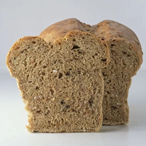 A slice of wholemeal bread in front of a loaf, close-up