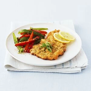 Veal Milanese served with bell peppers and lemon slices on plate