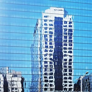 Cityscape reflected in glass facade of building