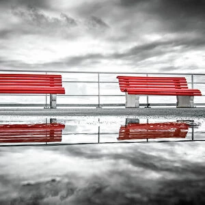 Reflection of two red benches in a puddle on La pier du Moulleau, La Teste-de-Buch, France