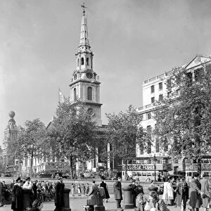 People feeding pigeons in Trafalgar Square with the church spire of St Martin