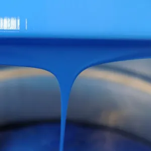 Blau Lack wird aus einem Eimer in einer Werkstatt im Raphael-Isabey-Sennelier eingegossen Blau Lack wird aus einem Eimer in einer Werkstatt im Raphael-Isabey-Sennelier eingegossen