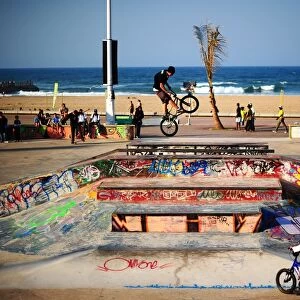 A BMX (Bicycle Motor Cross) rider performs on a ramp in a skatepark decorated with