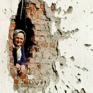 Print of a Bosnian-Muslim woman peeking from her damaged home near Zvornik Print of a Bosnian-Muslim woman peeking from her damaged home near Zvornik
