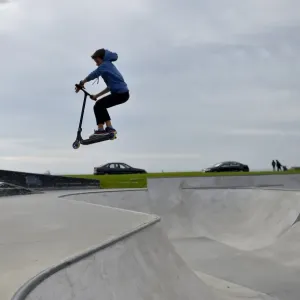 Print of a boy riding a scooter in a skate park Print of a boy riding a scooter in a skate park