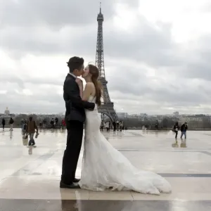 A Chinese maried couple kisses each other in front of the Eiffel tower on February 25
