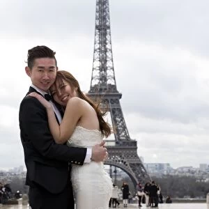 A Chinese maried couple pose in front of the Eiffel tower on February 25, 2014, in Paris