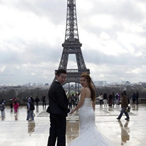 A Chinese maried couple poses in front of the Eiffel tower on February 25, 2014, in Paris