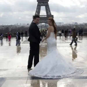 A Chinese maried couple poses in front of the Eiffel tower on February 25, 2014, in Paris