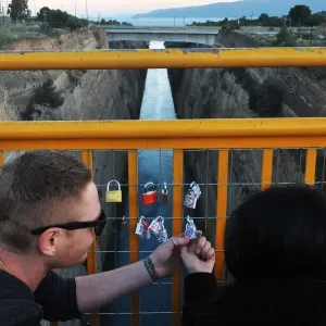 A couple looks at a love lock they attached to a bridge overlooking