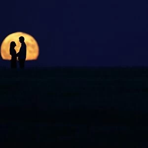 A couple stand in front of the full moon in Burgos on September 9, 2014