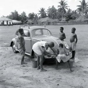 Print of a 1958 photograph showing African boys examining a Volkswagen Beetle model Print of a 1958 photograph showing African boys examining a Volkswagen Beetle model