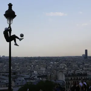 Iya Traore, a former professional football player, holds on to a lamppost as he performs Iya Traore, a former professional football player, holds on to a lamppost as he performs