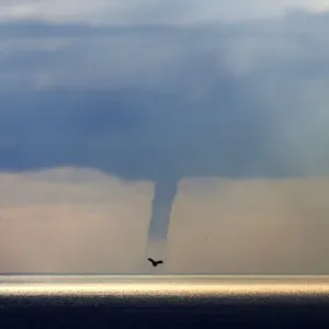 A waterspout forms on the horizon above the Mediterranean sea, off the coastal city A waterspout forms on the horizon above the Mediterranean sea, off the coastal city