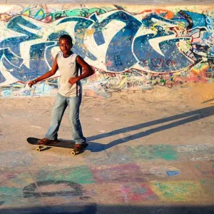 Print of a young boy skateboarding past graffiti in Durban, South Africa Print of a young boy skateboarding past graffiti in Durban, South Africa