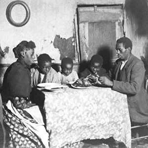 poor black people at dinner hacing chicken in a delapidated house