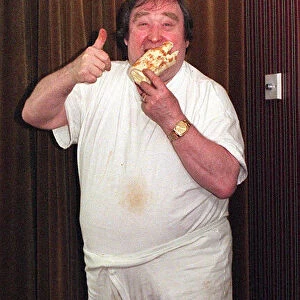 Bernard Manning comedian eating a Walls Arctic Roll dessert. September 1997