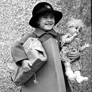 Happy young girl dressed up in coat and hat holding parcels under one arm