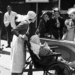 Nurses pushing a child in a wheelchair around Barts Fair, circa 1938