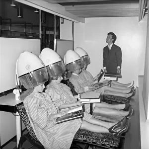 Women reading magazines at the John London Hair and Beauty Saloon whilst under the driers