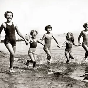 Young children running in the sea as they enjoy themselves on the beach at Bognor during