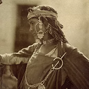 Half-length portrait of a young Arab-Berber girl in ethnic attire. She is wearing large earrings