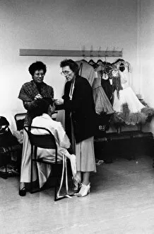 Two women help dancer in dressing room