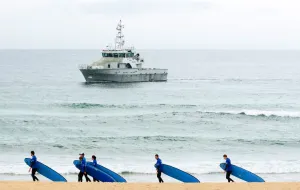 <b class=qtipBold><figcaption>Australia-Britain-Royals-Surfers</figcaption></b><br>Student surfers walk past a patrolling police boat on patrol before Britain's Prince Charles (unseen) attends an football on the beach exhibit. AFP PHOTO/John DONEGAN / AFP PHOTO / JOHN DONEGAN<br><em>© Copyright Agence France-Presse (AFP) - All Rights Reserved</em> Australia-Britain-Royals-Surfers