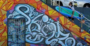 <b class=qtipBold><figcaption>AUSTRALIA-THEME-STREET ART</figcaption></b><br>A surfer walks past wall artwork on the promenade at Sydney's iconic Bondi Beach. AFP Photo / Greg WOOD / AFP PHOTO / GREG WOOD<br><em>© Copyright Agence France-Presse (AFP) - All Rights Reserved</em> AUSTRALIA-THEME-STREET ART