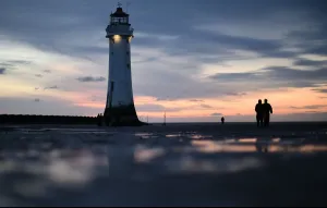 <b class=qtipBold><figcaption>Britain-Art-Lighthouse</figcaption></b><br>People walk along the beach at the mouth of the River Mersey at New Brighton, north-west England on April 23, 2016. Local businesses have raised funds to illuminate the decommissioned Perch Rock lighthouse which was first lit in 1830 and was in continuous use until October 1973. / AFP PHOTO / PAUL ELLIS<br><em>© Copyright Agence France-Presse (AFP) - All Rights Reserved</em> Britain-Art-Lighthouse
