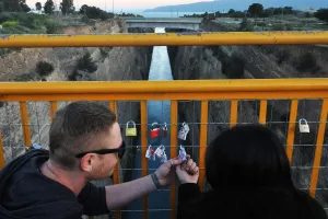 A couple looks at a love lock they attached to a bridge overlooking