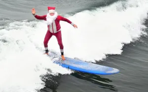 <b class=qtipBold><figcaption>US-HOLIDAY-SURFING-SANTA-OFFBEAT</figcaption></b><br>Surfing Santa, Michael Pless, waves while riding a wave at Seal Beach, California, on December 10, 2016, where he runs a surfing school and has every December since in 1990's gone out to surf in his Santa Claus outfit. / AFP PHOTO / Frederic J. BROWN<br><em>© Copyright Agence France-Presse (AFP) - All Rights Reserved</em> US-HOLIDAY-SURFING-SANTA-OFFBEAT