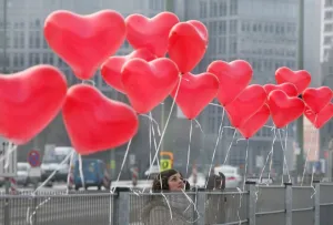 Saint Valentines Day Heart Prints: A woman fixes red heart-shaped balloons on a fence on Februray 14, 2012 in Berlin